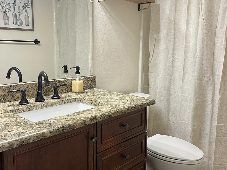 Full guest bathroom with granite vanity, updated fixtures, and tub-shower combination.