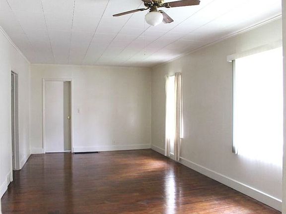 Large combination living room/dining room with refinished hardwood floors and large windows.