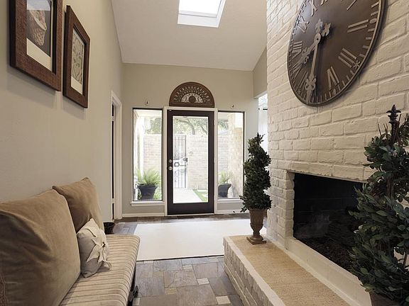 The extended generous foyer features a skylight, slate floor, gas log fireplace with brick surround with access to back patio. Perfect spot to relax and read by the fire or drink your morning coffee.