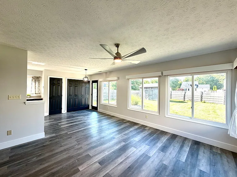 Large living and dining area with huge windows, overlooking fanced back yard, High end ceiling fan, flat screen tv mount and solid surface flooring.