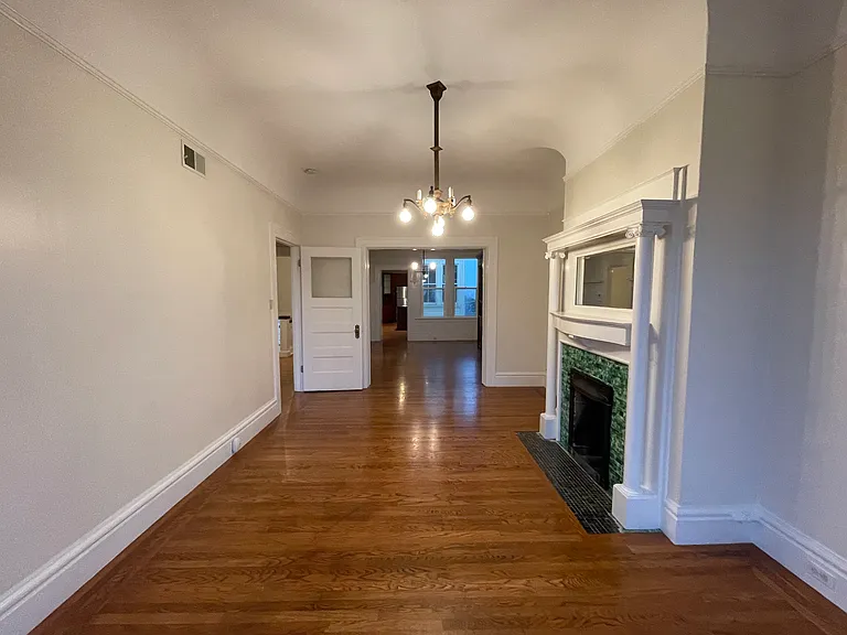 Bedroom Two with Decorative Fireplace & Pocket Doors Leading to Living Room