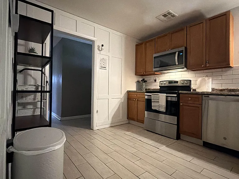 Functional kitchen with upper wood cabinetry, tile flooring, and stainless range with over-the-range microwave and dishwasher
