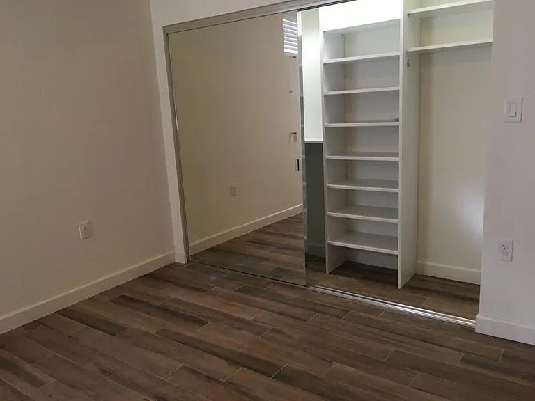 Second bedroom with built-in shelving in closet.