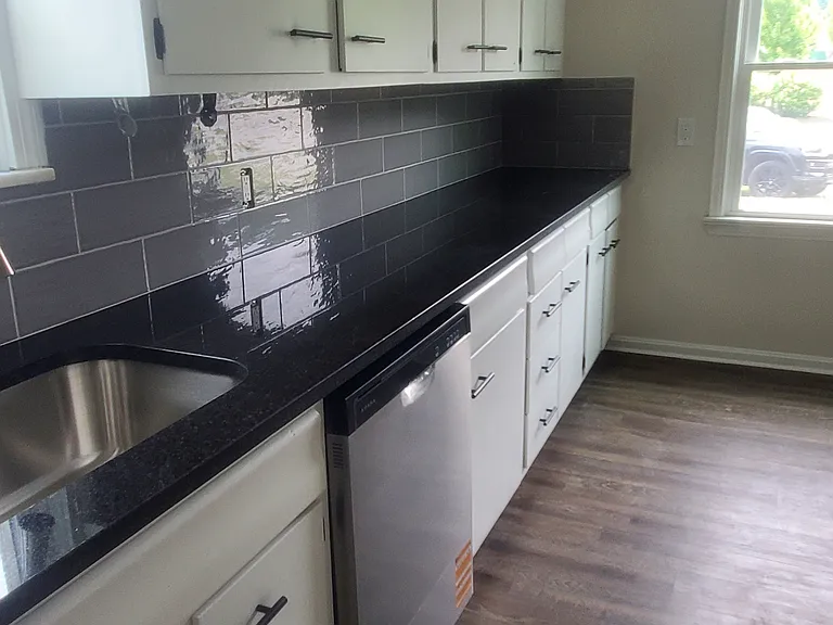 Glamour kitchen with sleek white cabinets and black granite countertops. new stainless dishwasher and rangehood