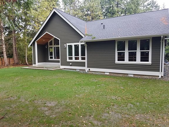 Back of house with lots of windows looking towards the wooded area