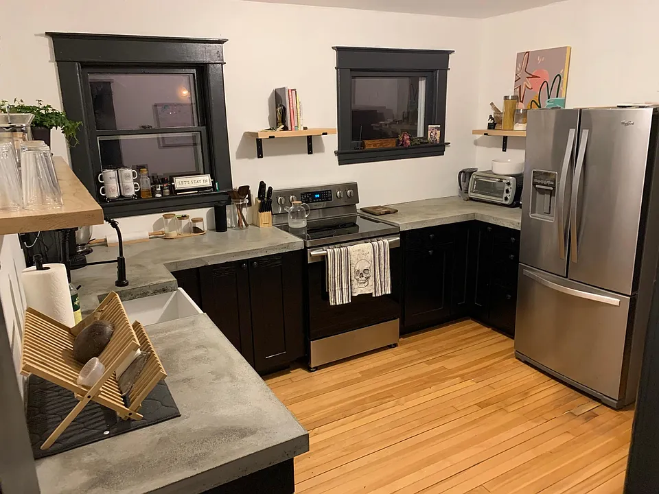 Spacious kitchen with concrete counter tops, dishwasher, new range and large refrigerator.