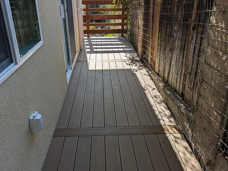 Private deck with modern plank flooring and a secure perimeter. This peaceful retreat includes a dedicated pet area and stunning views of the valley mountain range_perfect for enjoying summer sunsets with your furry friend. Plenty of room for seating.