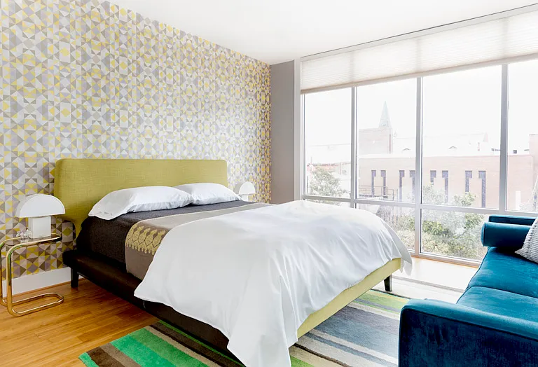 Office and guest suite features a queen bed, sofa, standing desk and Samson monitor adn a full wall of floor to ceiling window.