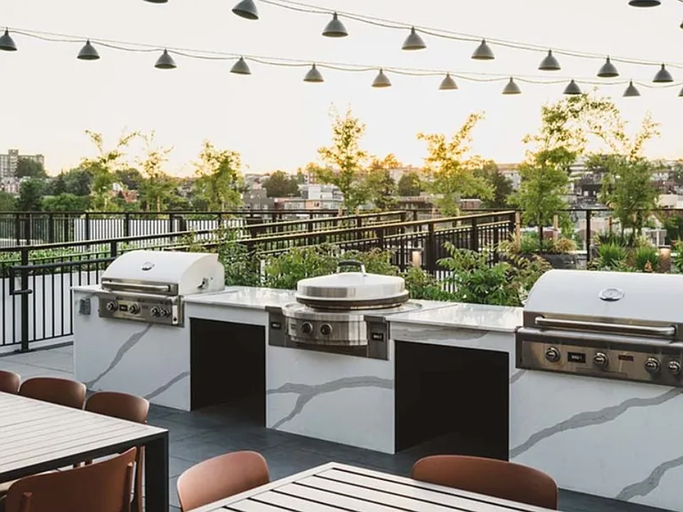 The rooftop at Modera Broadway beckons with string lighting and grilling stations perfect for gathering outdoors