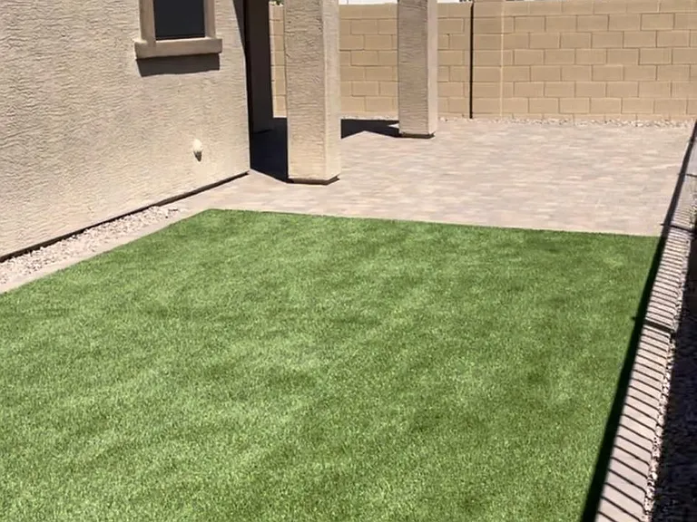 New synthetic grass and pavers in backyard.