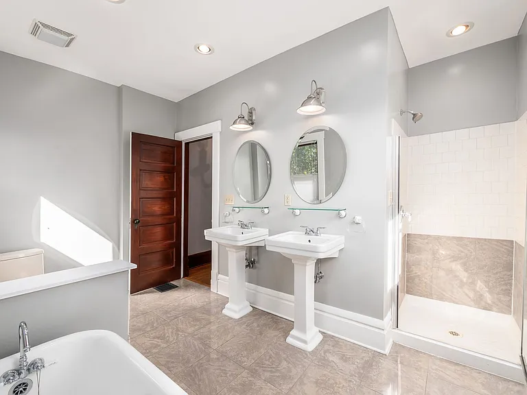 Bathroom features marble floors and shower surround, plentiful natural light, exhaust fan, and clawfoot tub.