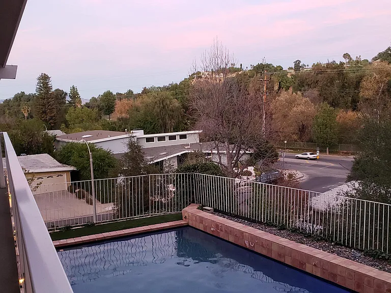 View from wrap around glass balcony overseeing pool and neighborhood.