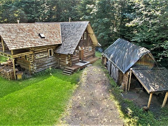 Entrance on the right side of log cabin, storage building on the right with carport to park under on the far right!
