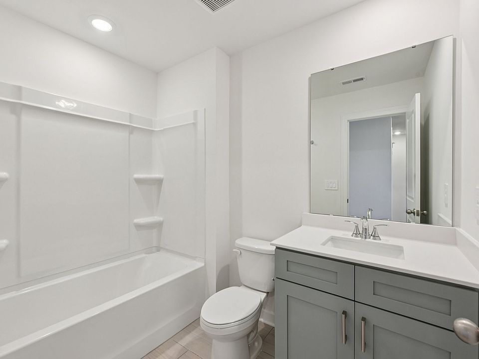 The secondary bathroom features a storage vanity and oversized shower tub.
