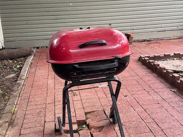 Weber grill available for tenant use on brick side yard patio in fenced yard.