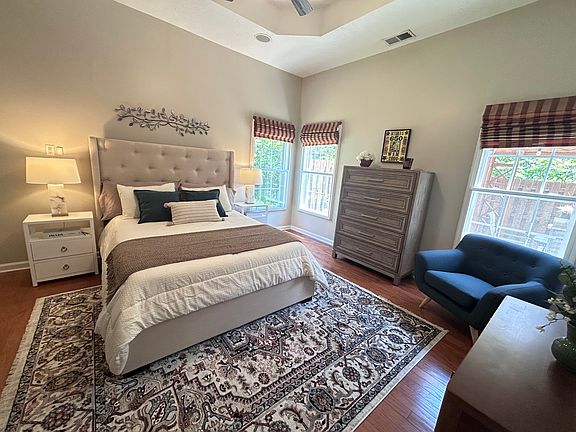 Primary bedroom downstairs with tray ceiling, Roman shades, walk-in custom closet, ensuite bathroom. Windows face hillside (no neighbors) and back patio for total privacy.