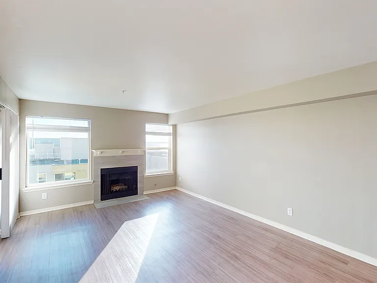 Apartment living room with wood-style flooring, fireplace and balcony in select homes.