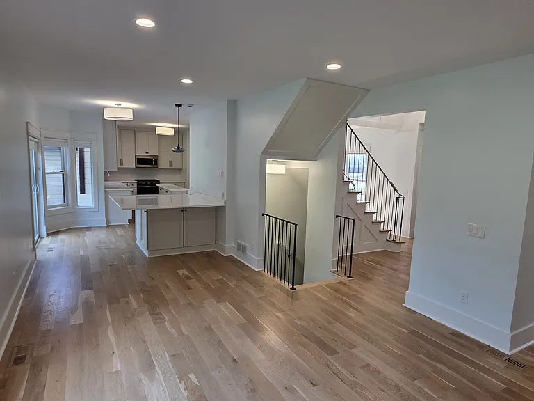 View from living room into kitchen and showing stairs to basement and upper floor where bedrooms are.