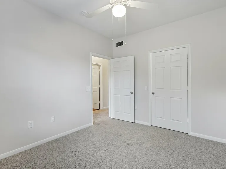 Bright and airy bedroom with plush carpeting, neutral walls, and a ceiling fan for comfort. Bright and airy bedroom with plush carpeting, neutral walls, and a ceiling fan for comfort.