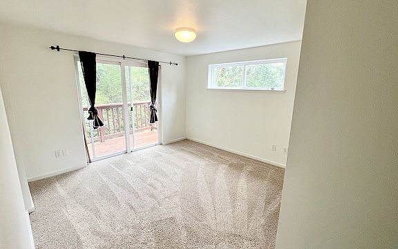 Bedroom one, third floor. Deck through sliding doors looks over the forested fully fenced backyard.