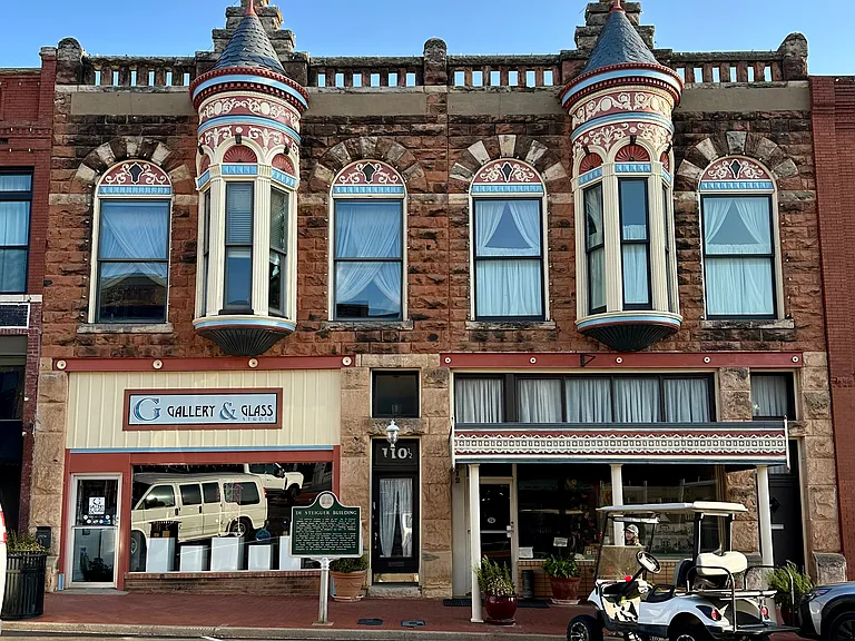 The historic De Steiguer Building- actually two buildings, cleverly designed to look like one. Built in 1890, its distinctive facade features Oklahoma's native red sandstone, making it one of Guthrie's most recognizable historic landmarks.