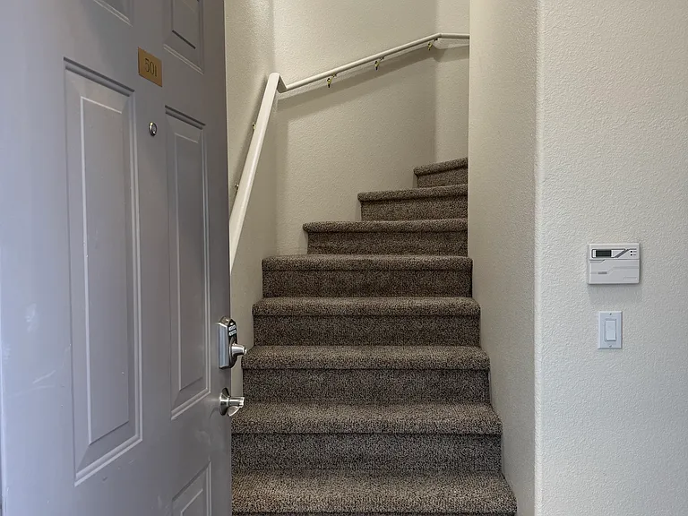 Entryway with stairs up to living area. Door to the one-car garage is to the right of the stairs.