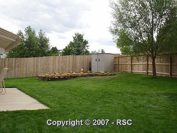 View of backyard with planting area and storage shed.