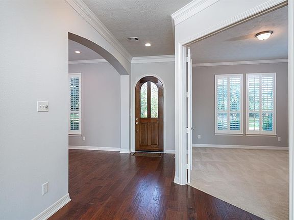 An arched leaded glass door opens to gorgeous hand-scraped wood flooring that flows into the formal dining room and down the hallway into the family room!