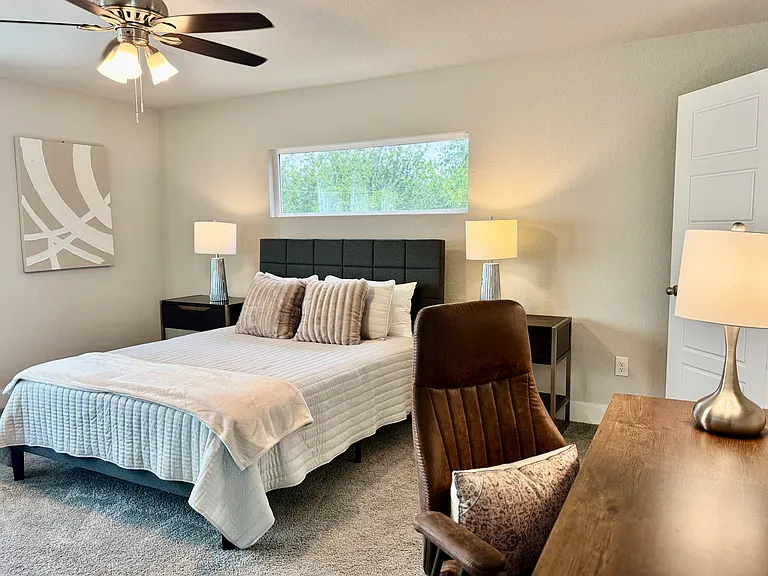 Master bedroom features a queen bed, desk/chair, dresser and seating area