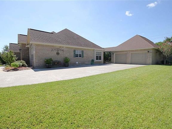 View of the garage and side of the home. There is ample concrete for additional parking. This home features a full yard & flower bed sprinkler system, a recent 5 ton AC (July 2011), and lots of lovely living space!
