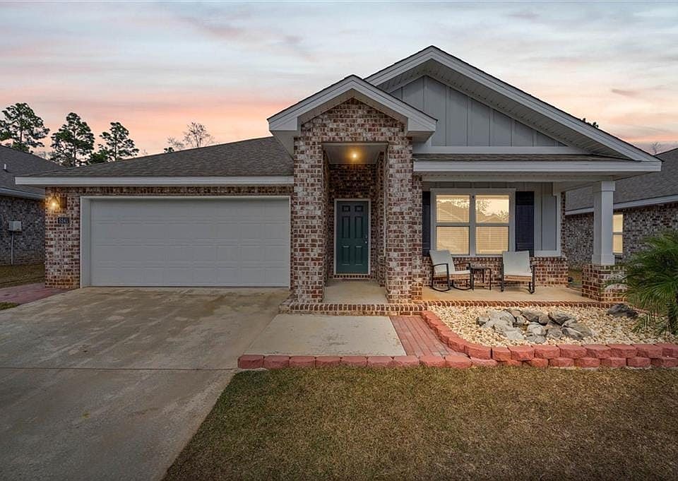 Craftsman-style house with board and batten siding, an attached garage, brick siding, and driveway