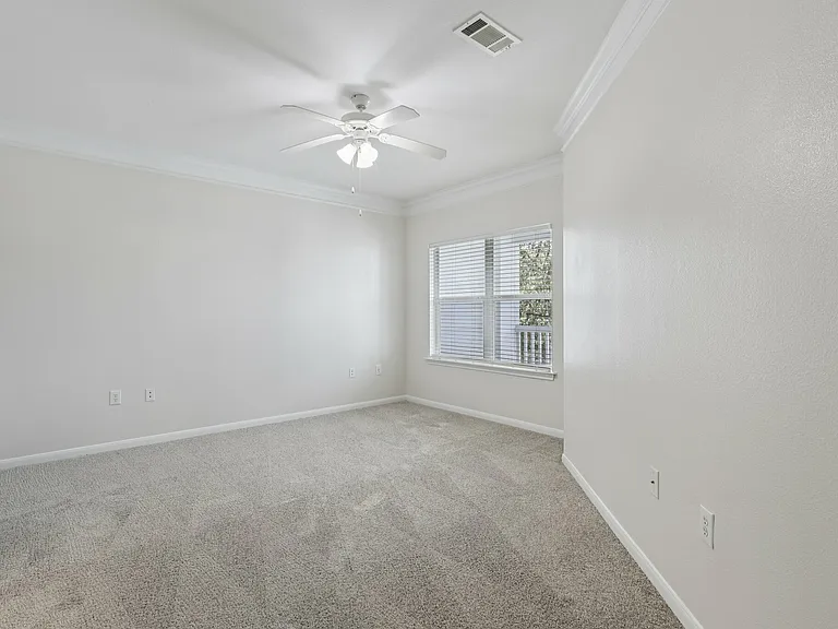 Bright and airy bedroom with plush carpet, large window, and ceiling fan, offering a cozy and inviting atmosphere. Bright and airy bedroom with plush carpet, large window, and ceiling fan, offering a cozy and inviting atmosphere.