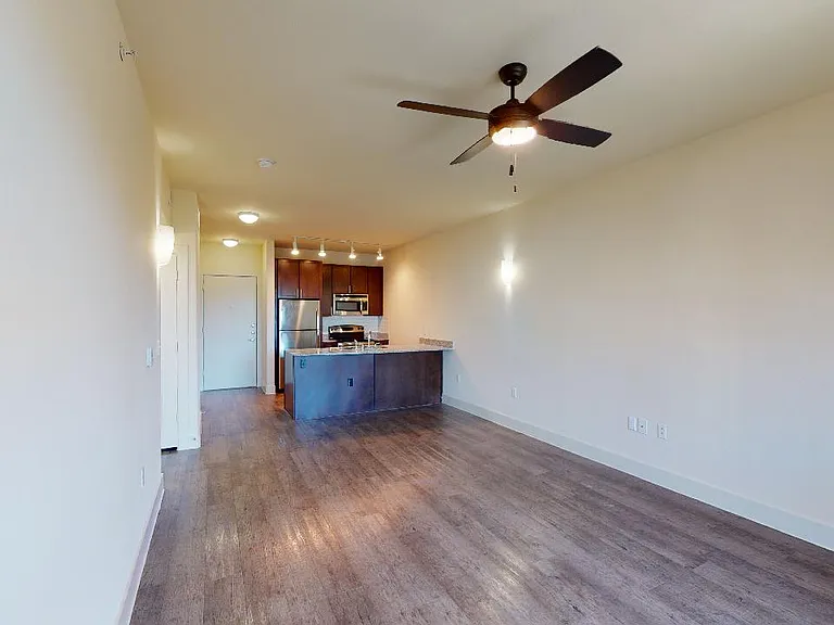 Apartment kitchen with stainless steel appliances in select homes, dining and living room with wood-style flooring.