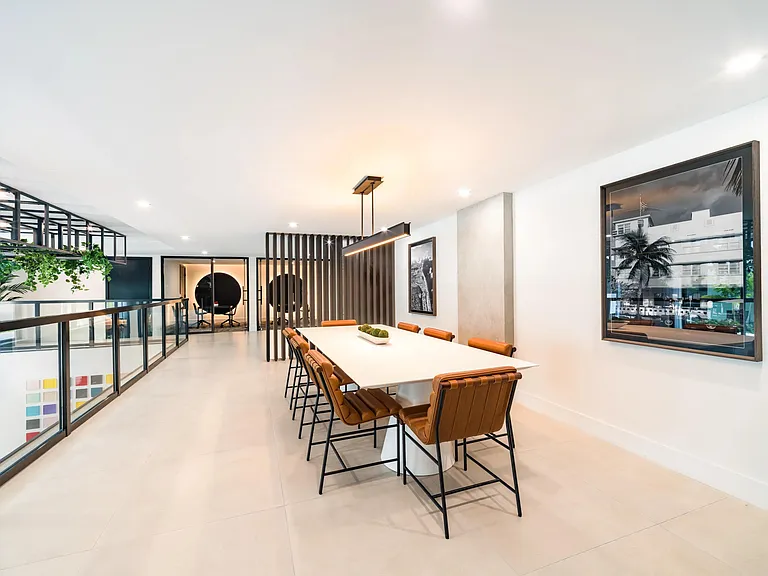 Communal dining table with seating for larger gatherings, contemporary lighting, and adjacent coworking spaces designed for collaboration and connection.