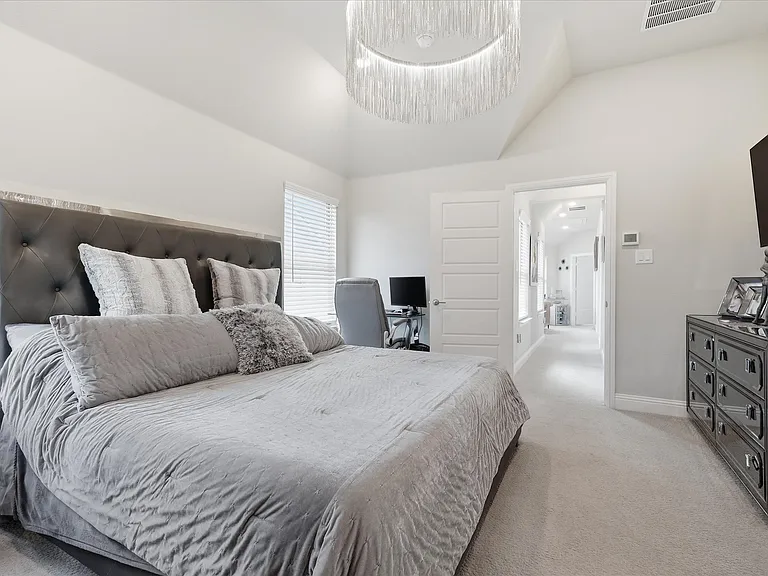 Spacious primary bedroom with high ceilings, recessed lighting, and a contemporary chandelier.
