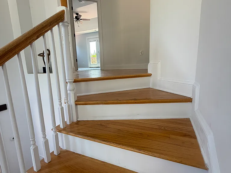 Straightflight staircase linking the main level directly to the second floor, opening to both the shared upper sitting space and the private primary suite.