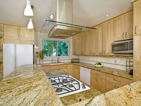 Efficient custom kitchen has gorgeous slab granite counters all around. 