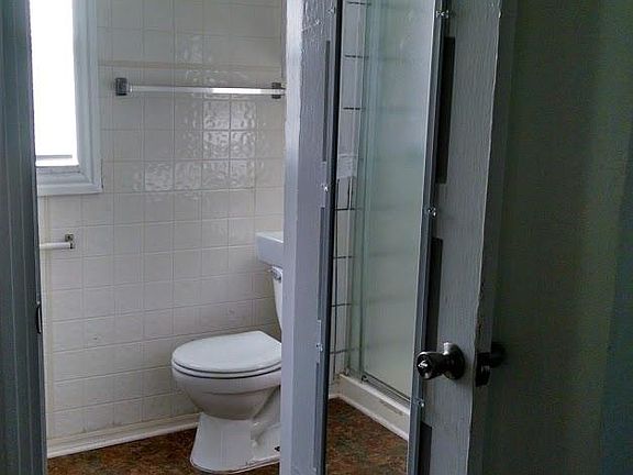 View of the bathroom entrance with new flooring and a mirror on the door.