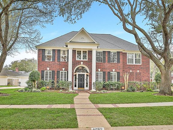 The home is framed with mature shrubs and trees and the dramatic pillars add a touch of elegance.