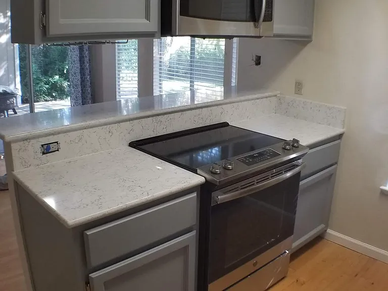 Kitchen cooking island. New Stove Oven, and microwave with Single slab preparation areas on either side, storage above and below, and serving counter to dining room.