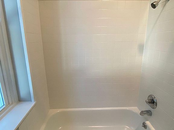 nice tub/shower combo with natural light from large window