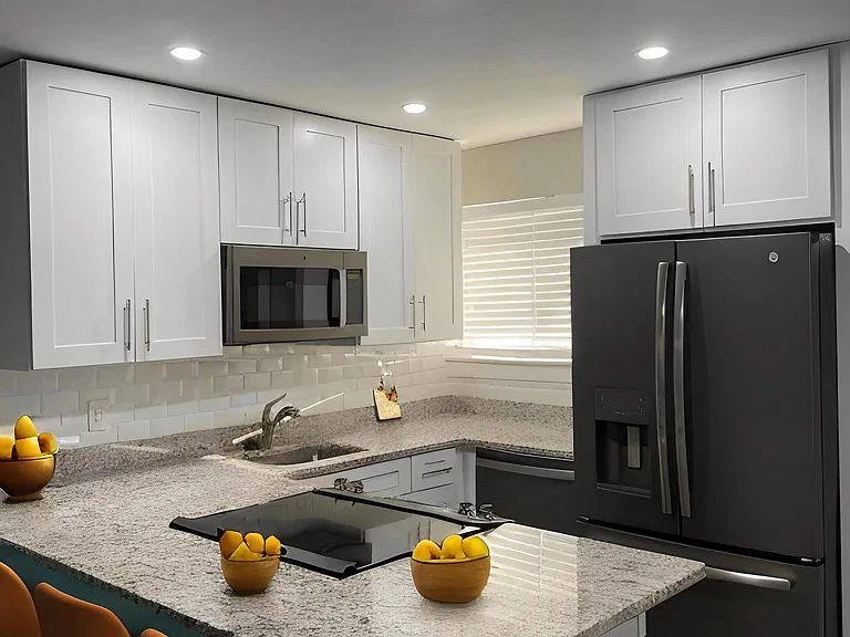 Open concept Kitchen with large granite island, stainless steel appliances. Oversized white shaker cabinets to ceiling, and recessed lighting.