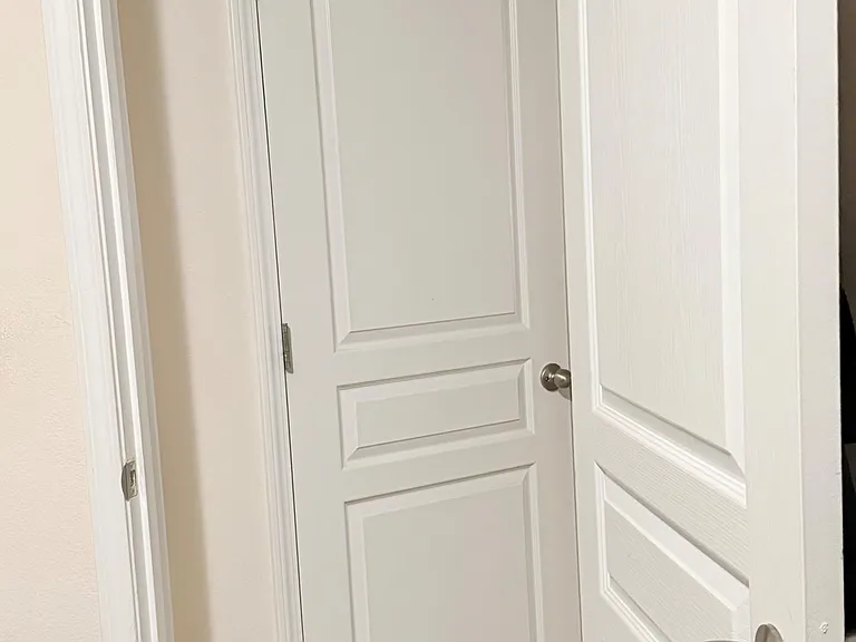 Interior hallway area with paneled doors and neutral finishes providing access to nearby rooms and storage.