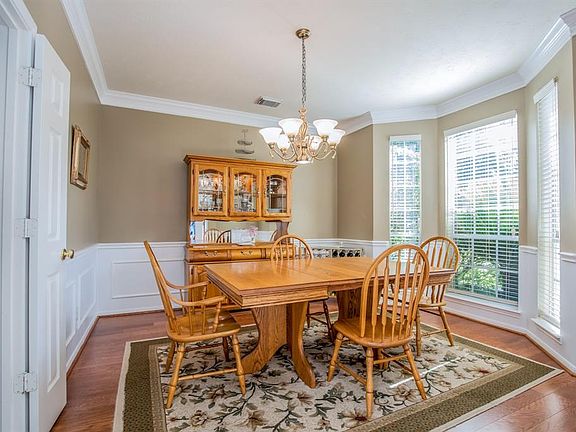 Dining room welcomes with wood floors, thick moldings, contrasting neutral paint and white trim, 2" blinds and lovely bay window.