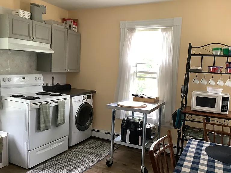 Kitchen with stainless steel chef's table on wheels, combo washer/dryer, air-fryer, etc