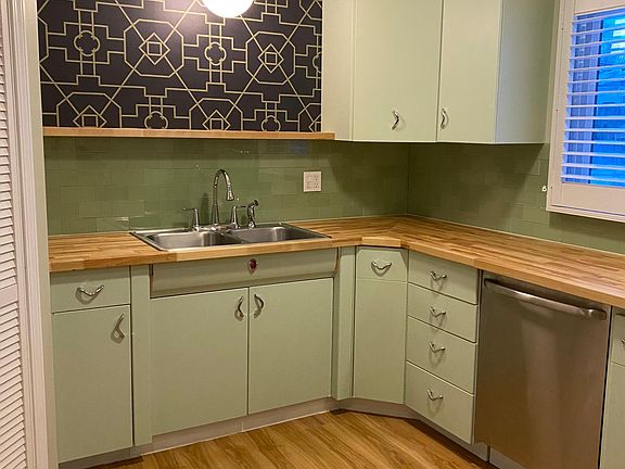 Vintage metal cabinets, butcher block counters, stainless dishwasher, plantation shutters, display shelf, garbage disposal