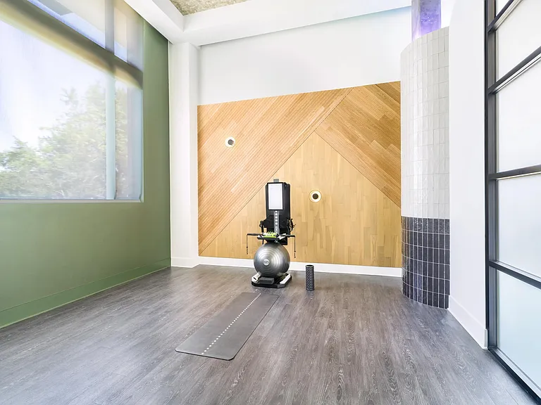 Wellness studio with open floor space, strength equipment, and natural light designed for focused training, stretching, and recovery routines.