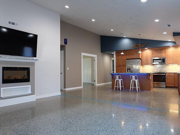 Open plan with loft ceilings make for an impressive entry. A digital fireplace projects ambiance and warms the area. The breakfast bar features color-changeable under-counter lighting. Polished concrete floors are durable, attractive and easy to clean.