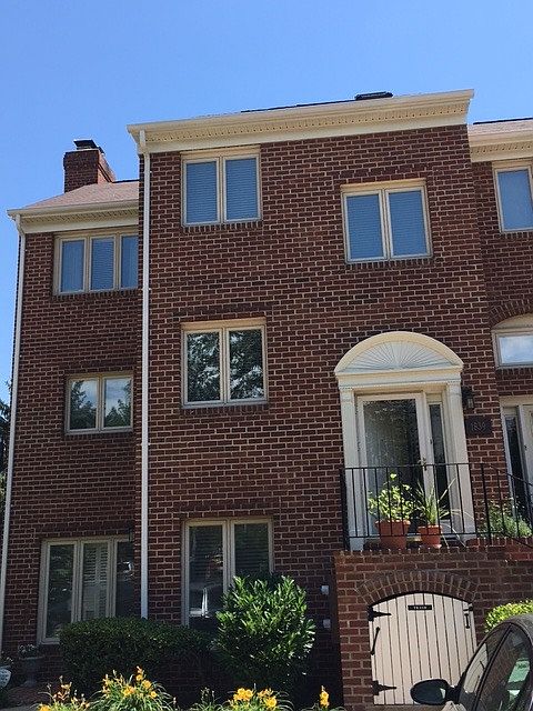 Two-story townhouse in green setting.