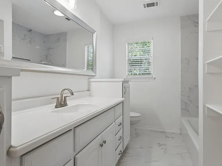 Full bath featuring marble look tiles, vanity, toilet, and baseboards